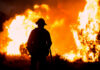 Largest wildfire in the US spreading fast through Utah Silhouette of a firefighter standing in front of a large wildfire