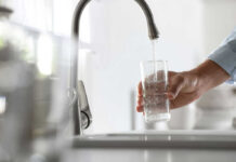 Nitrate in Tap Water May Raise Your Dementia Risk A hand holding a glass under a kitchen faucet while water is being poured into it