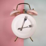 An alarm clock with a plate and two forks arranged in a creative design