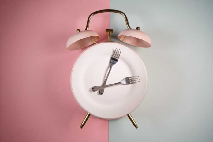 Alarm,Clock,And,A,Plate,With,Fork,And,Knife.,Time An alarm clock with a plate and two forks arranged in a creative design