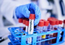Blood Test Twist Upends Depression Playbook A gloved hand holding a test tube labeled 'Legionella' among other samples