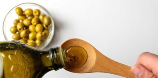 Pouring olive oil from a bottle into a wooden spoon