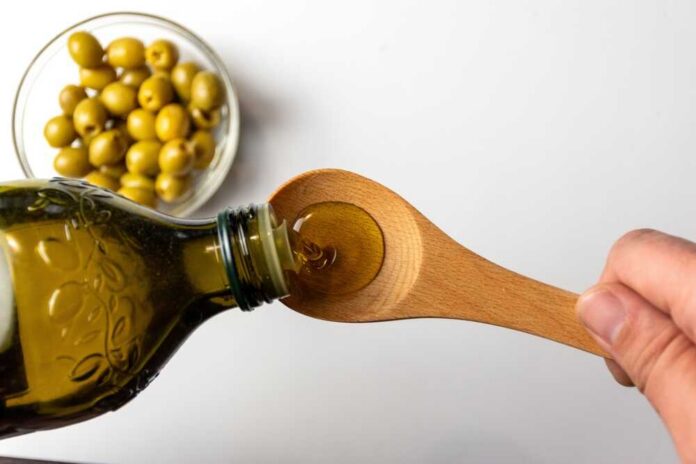 Olives,With,Extra,Virgin,Olive,Oil Pouring olive oil from a bottle into a wooden spoon