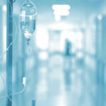 Why Cancer Treatments Stop Working For So Many Patients IV drip in a hospital corridor with a blurred background