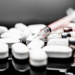 Depression Breakthrough: Hallucination-Free Brain Drugs White pills and syringes arranged on a reflective surface