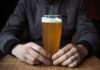 Early-Onset Cancer’s Hidden Accomplice Person holding a glass of craft beer in a bar