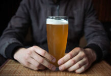 Early-Onset Cancer’s Hidden Accomplice Person holding a glass of craft beer in a bar