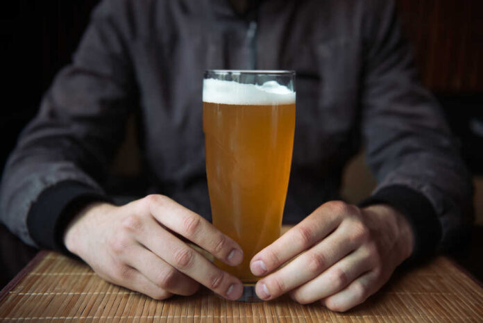 Man,Holding,Glass,Of,Beer Person holding a glass of craft beer in a bar