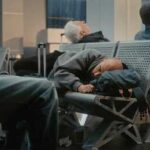 Passengers sleeping on airport benches with luggage nearby