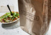 Hidden Salt Trap in Takeaways A Chipotle takeout bag next to a bowl filled with fresh salad ingredients