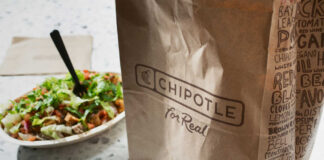 A Chipotle takeout bag next to a bowl filled with fresh salad ingredients