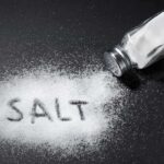 Salt shaker spilling salt on a dark surface