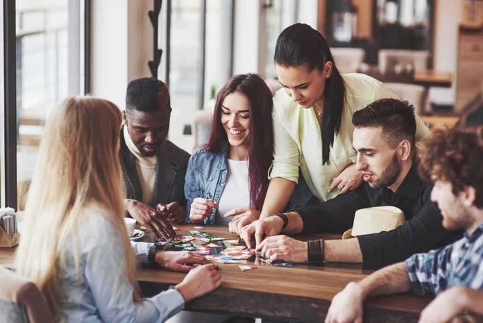 shutterstock_1052739101 Group of friends playing a board game at a table