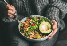 person holding a bowl of salad with avocado