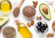 Plant Fats vs. Heart Attack Risk Assorted healthy fats with avocados, nuts, seeds, olives, and oils on a white background