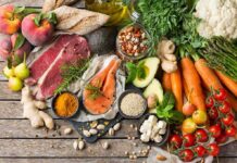 Assorted fresh ingredients with meat, salmon, fruits, and vegetables on a rustic table