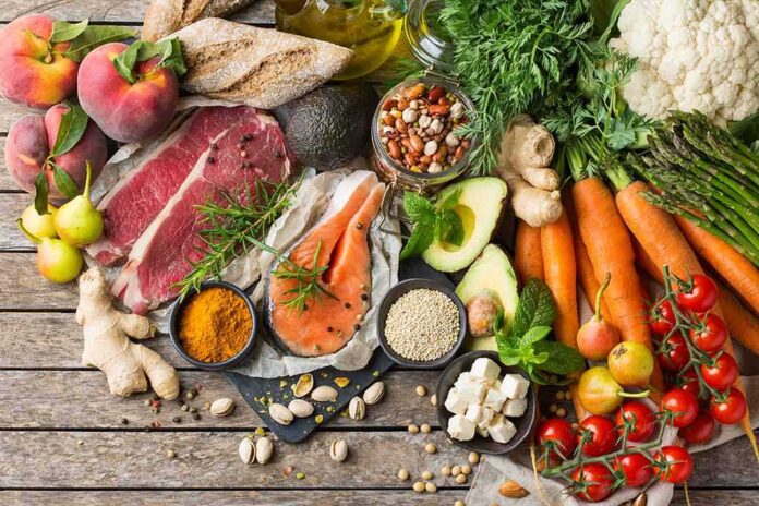 Assorted fresh ingredients with meat, salmon, fruits, and vegetables on a rustic table