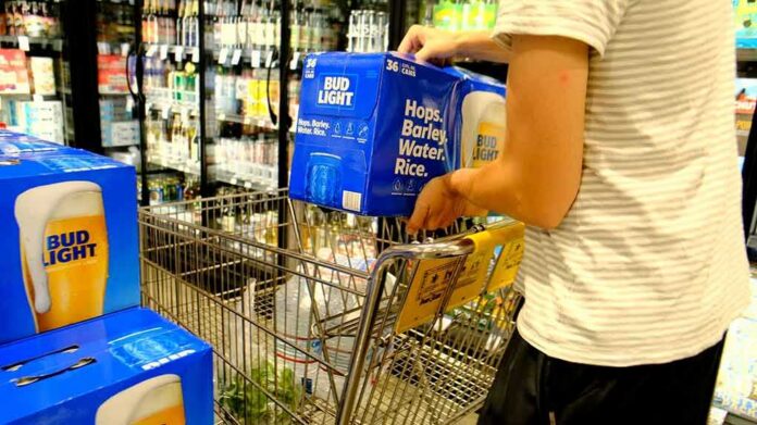 shutterstock_1555748012 Shopper loading cases of beer into a grocery cart