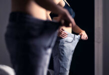 Person trying on oversized pants in front of a mirror