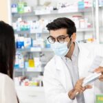 The billion-dollar problem keeping GLP-1 drugs from patients Pharmacist wearing mask explains medication to customer