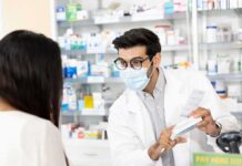 Pharmacist wearing mask explains medication to customer