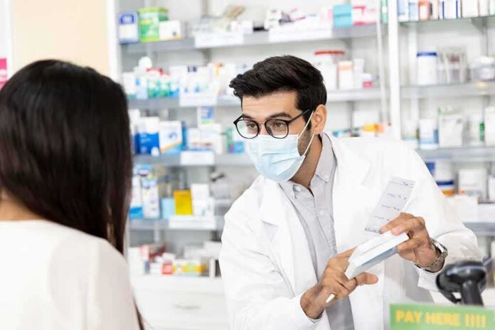 Pharmacist wearing mask explains medication to customer
