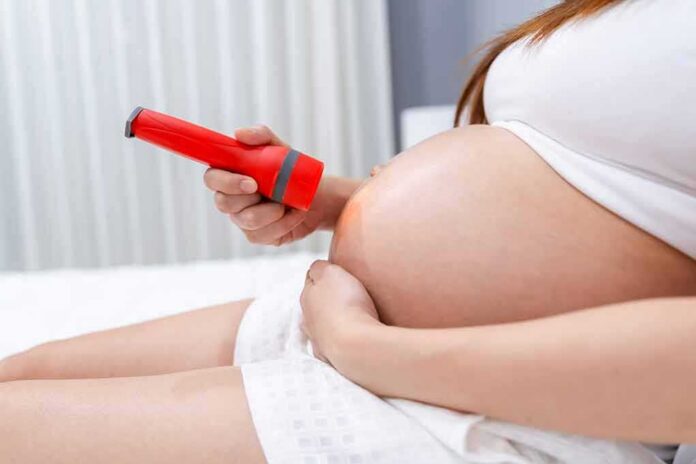 shutterstock_1860931993 Pregnant woman shining flashlight on bare belly