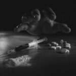 A hand reaching for pills next to a syringe and powder on a table