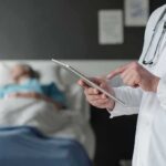 Shocking Gap: Cancer Patients Denied Relief Doctor using tablet beside hospital patient