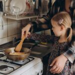 CDC Warning: Kitchen Habits That Cause Foodborne Illnesses Child cooking with adult at a stove