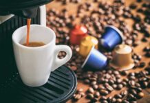 Your Coffee Maker Could Be Exposing You to Microplastics Espresso machine pouring coffee into a white cup with coffee pods and beans