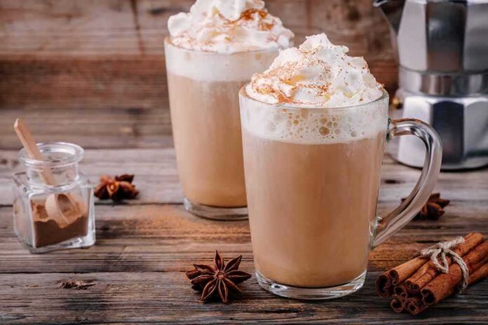 shutterstock_748158151 Two latte mugs with whipped cream and cinnamon on a rustic table