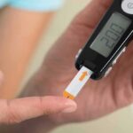 person using a blood glucose meter with a test strip