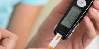 person using a blood glucose meter with a test strip