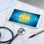 Tablet with FDA on screen amid medical tools and ECG charts