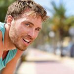 man in athletic tank top resting outdoors