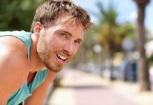 man in athletic tank top resting outdoors