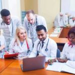 Medical students gathered around a laptop in a classroom