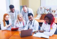 Medical students gathered around a laptop in a classroom