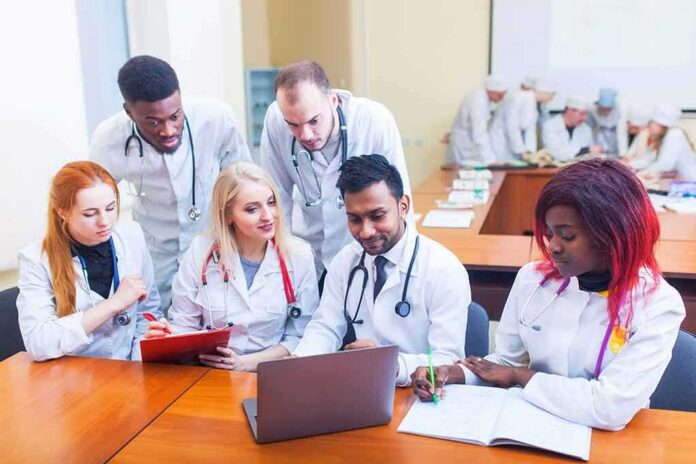 Medical students gathered around a laptop in a classroom