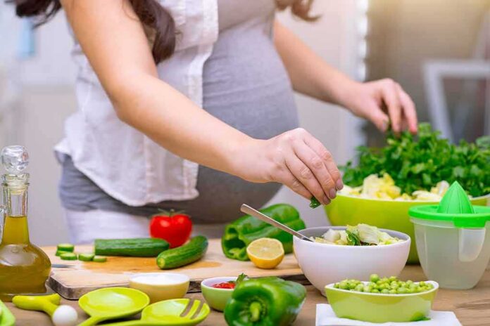 shutterstock_1038118966 Person preparing a fresh salad with green vegetables in a kitchen