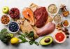 Assorted healthy foods with salmon, beef, chicken, fruits, vegetables, nuts, and grains