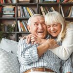 Senior couple hugging and laughing on a couch