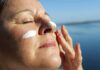 Woman applying sunscreen near water