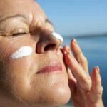 Woman applying sunscreen near water