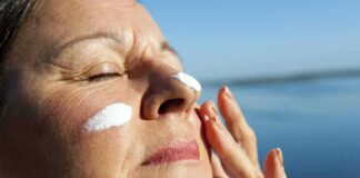 Woman applying sunscreen near water