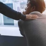 person comforting a man with a hand on his shoulder