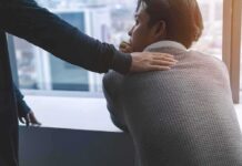 person comforting a man with a hand on his shoulder