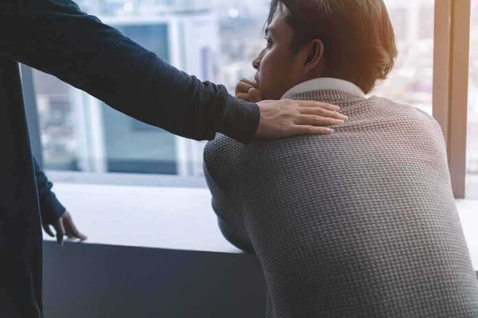 shutterstock_1142776922 person comforting a man with a hand on his shoulder