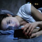 Comparison Trap: Engineered and Addictive Woman lying in bed looking at a smartphone
